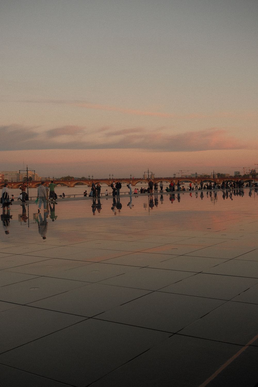 People reflected in a shallow water mirror at dusk
